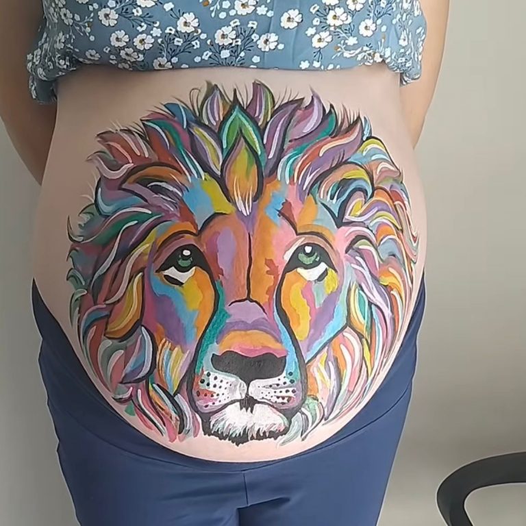 Bellypaint de una cabeza de león de colores en la tripa de una embarazada
