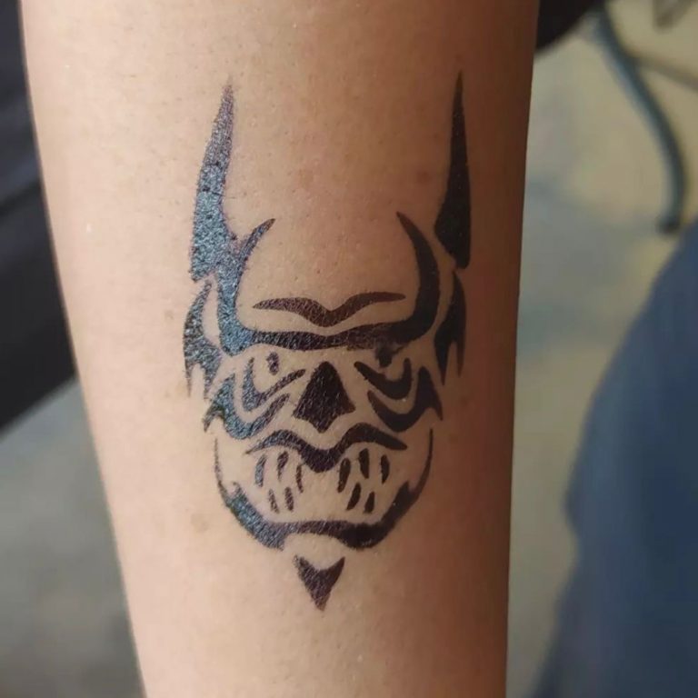 Tatuaje temporal con aerógrafo de una máscara en el brazo