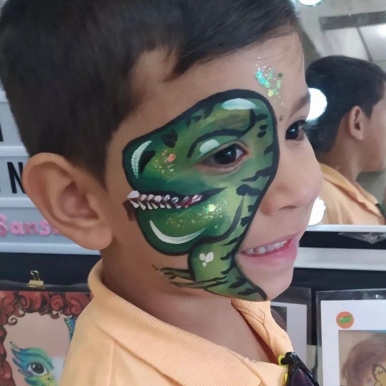 Niño con maquillaje de dinosaurio verde alrededor del ojo