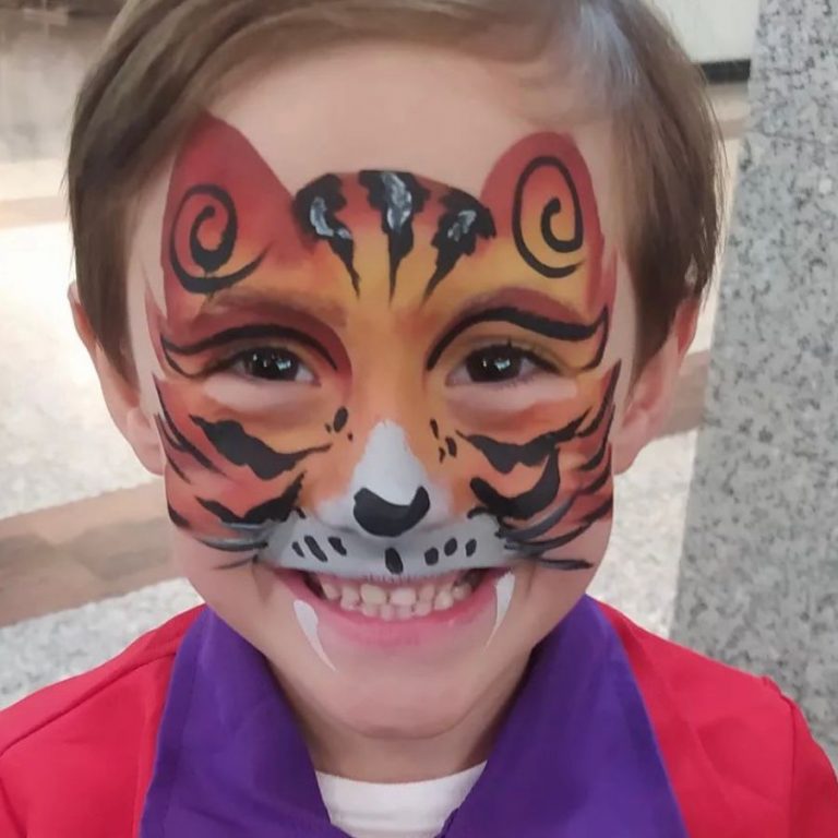 Niño con la cara pintada de tigre naranja y negro