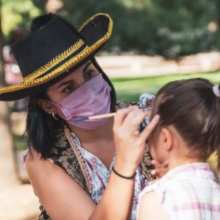 Animadora de Sandra Pintacaras maquillando la cara de una niña en una fiesta al aire libre